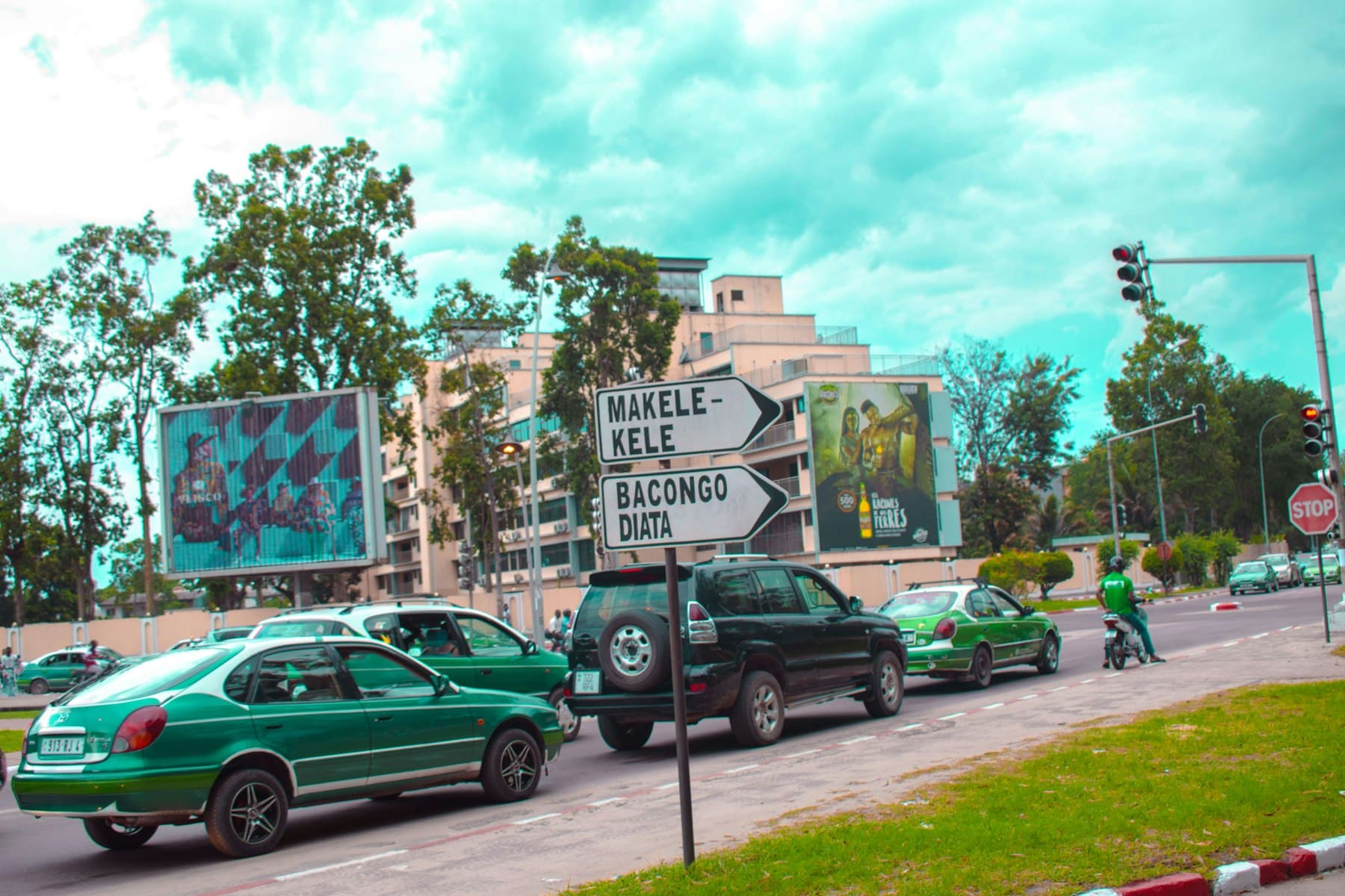Taxis verts dans une avenue de Brazzaville, devant les panneaux Makélékélé et Bacongo