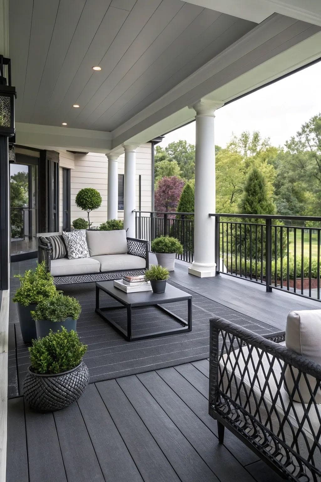Terrasse couverte d'une maison, avec un canapé, des plantes et une vue sur le jardin